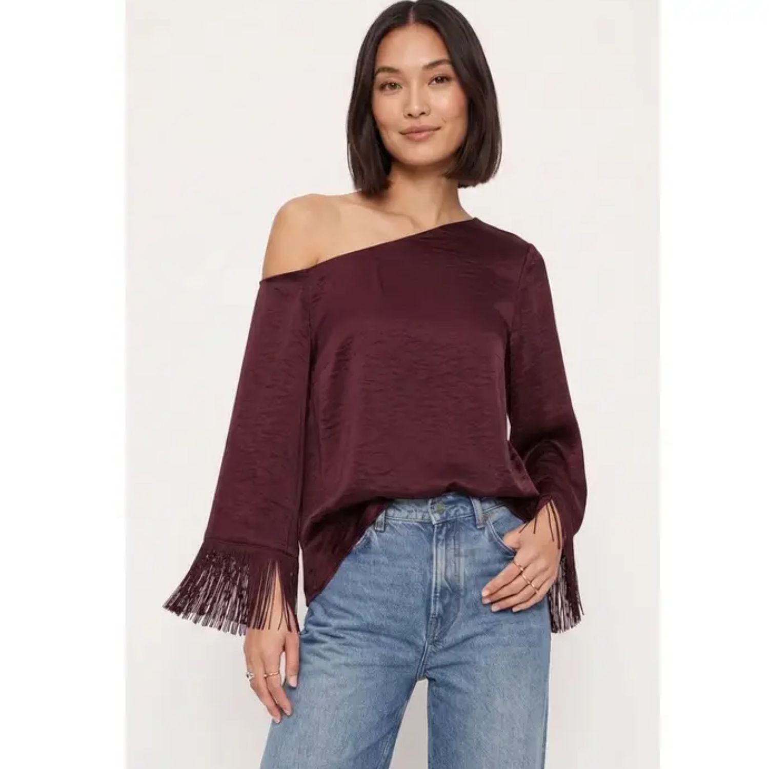 Off-shoulder satin blouse with an asymmetrical neckline and fringe-trimmed sleeves