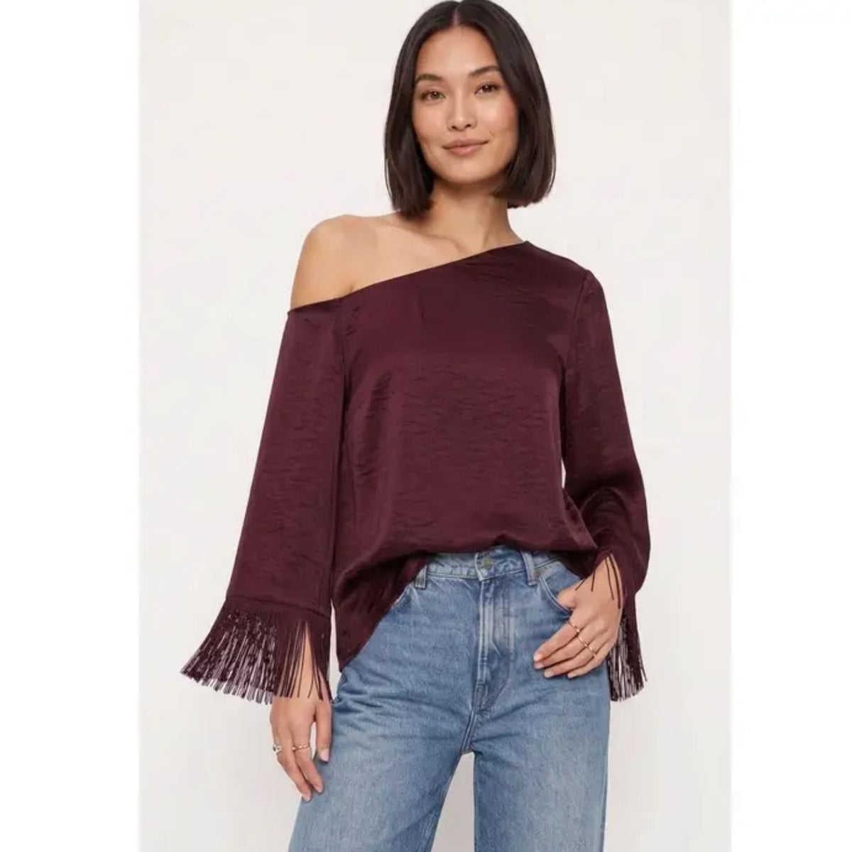 Off-shoulder satin blouse with an asymmetrical neckline and fringe-trimmed sleeves