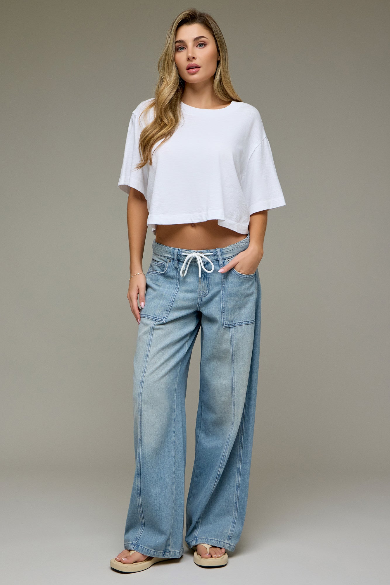 Light wash wide leg denim pants with drawstring waistband and front utility pockets paired with a cropped white tee.