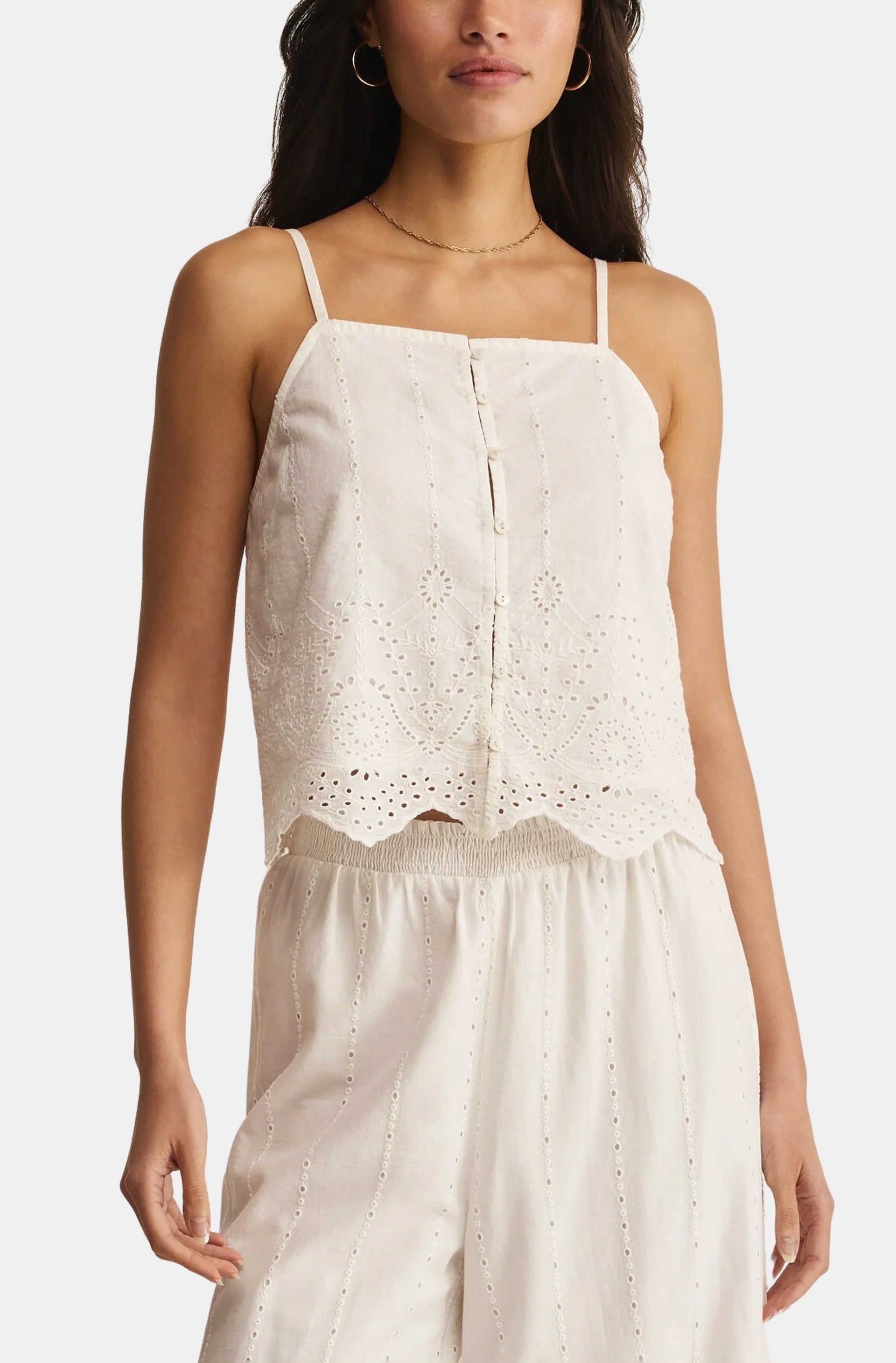 Sleeveless eyelet tank with thin straps, button-front detail, and scalloped hem, styled with matching flowy pants