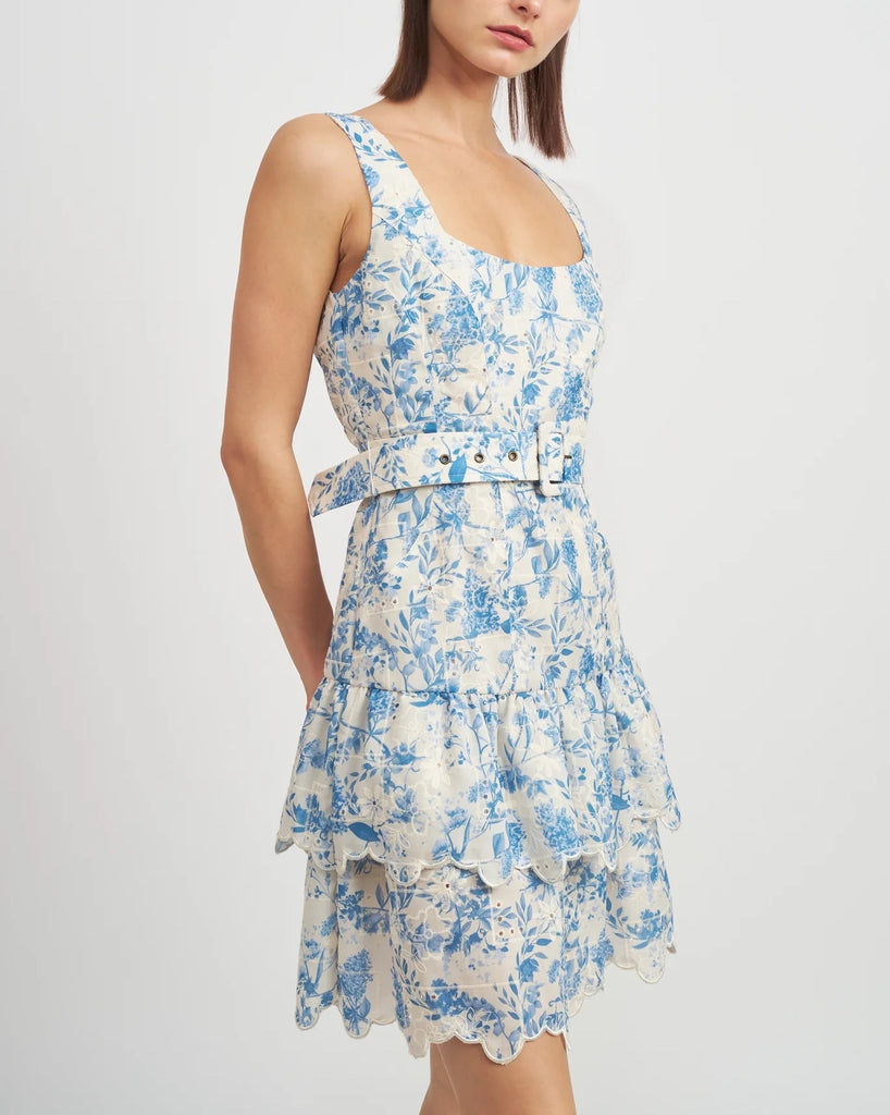 En Saison Davina Mini Dress Blue. This embroidered ruffled hem mini dress features a floral design with a belted waist and square neckline, the perfect chic sophisticated dress for a special occasion.