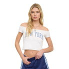 Model wearing an off-the-shoulder cropped New York graphic tee with a fitted silhouette paired with casual bottoms