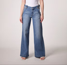 Woman wearing mid rise wide leg denim jeans with a relaxed fit and full length silhouette styled with a fitted tank