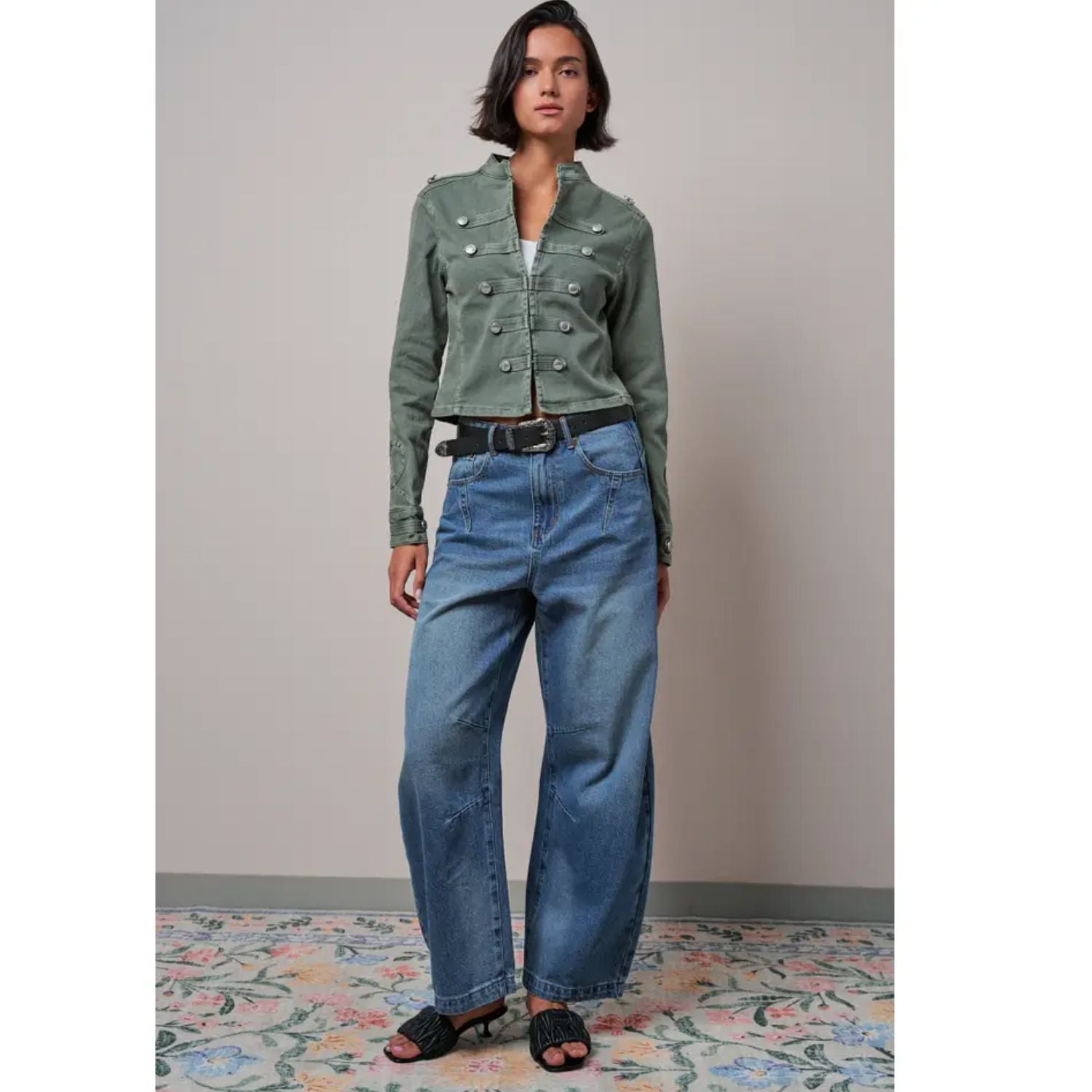 Military-inspired fitted denim jacket with a stand collar, decorative button tabs, and elbow patches