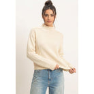 Moonbeam Mock Neck Sweater in cream with long sleeves, reversed seam detailing, and ribbed cuffs and hem.