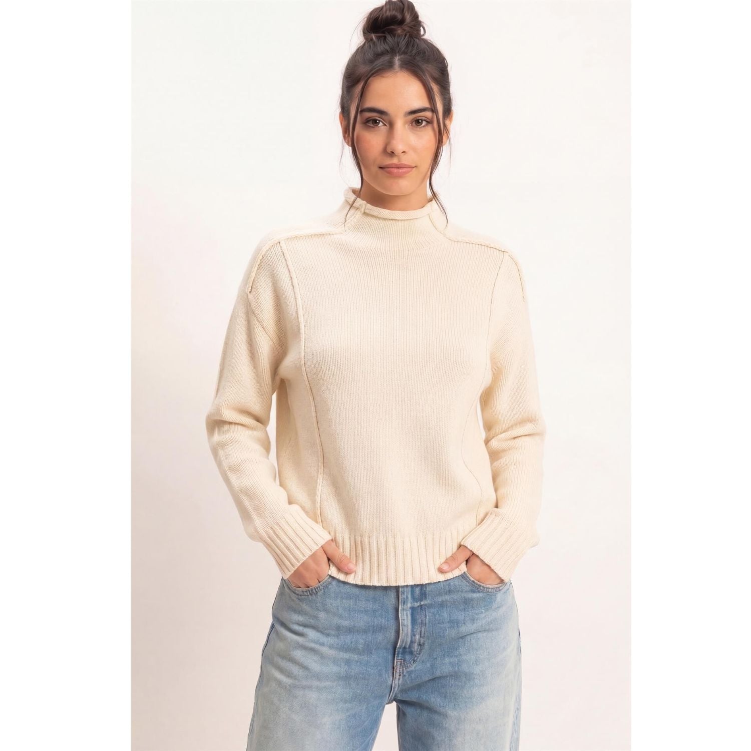 Moonbeam Mock Neck Sweater in cream with long sleeves, reversed seam detailing, and ribbed cuffs and hem.