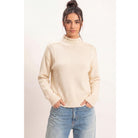 Moonbeam Mock Neck Sweater in cream with long sleeves, reversed seam detailing, and ribbed cuffs and hem.