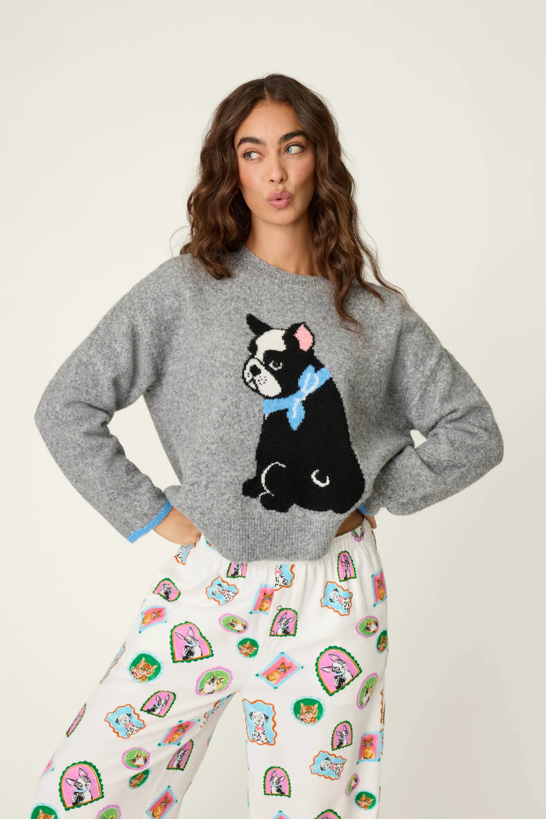 Woman wearing a crewneck sweater with a large French bulldog graphic and contrast cuff trim.