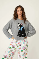 Woman wearing a crewneck sweater with a large French bulldog graphic and contrast cuff trim.