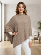 Woman wearing a knit poncho with a button-front collar and asymmetric hem.