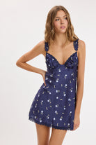 Model wearing a satin floral print slip dress with lace trim, adjustable lace shoulder straps, a sweetheart neckline, and a relaxed mini-length silhouette.