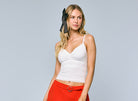Woman wearing a lace trim cami with a fitted silhouette and delicate detailing, styled with a skirt