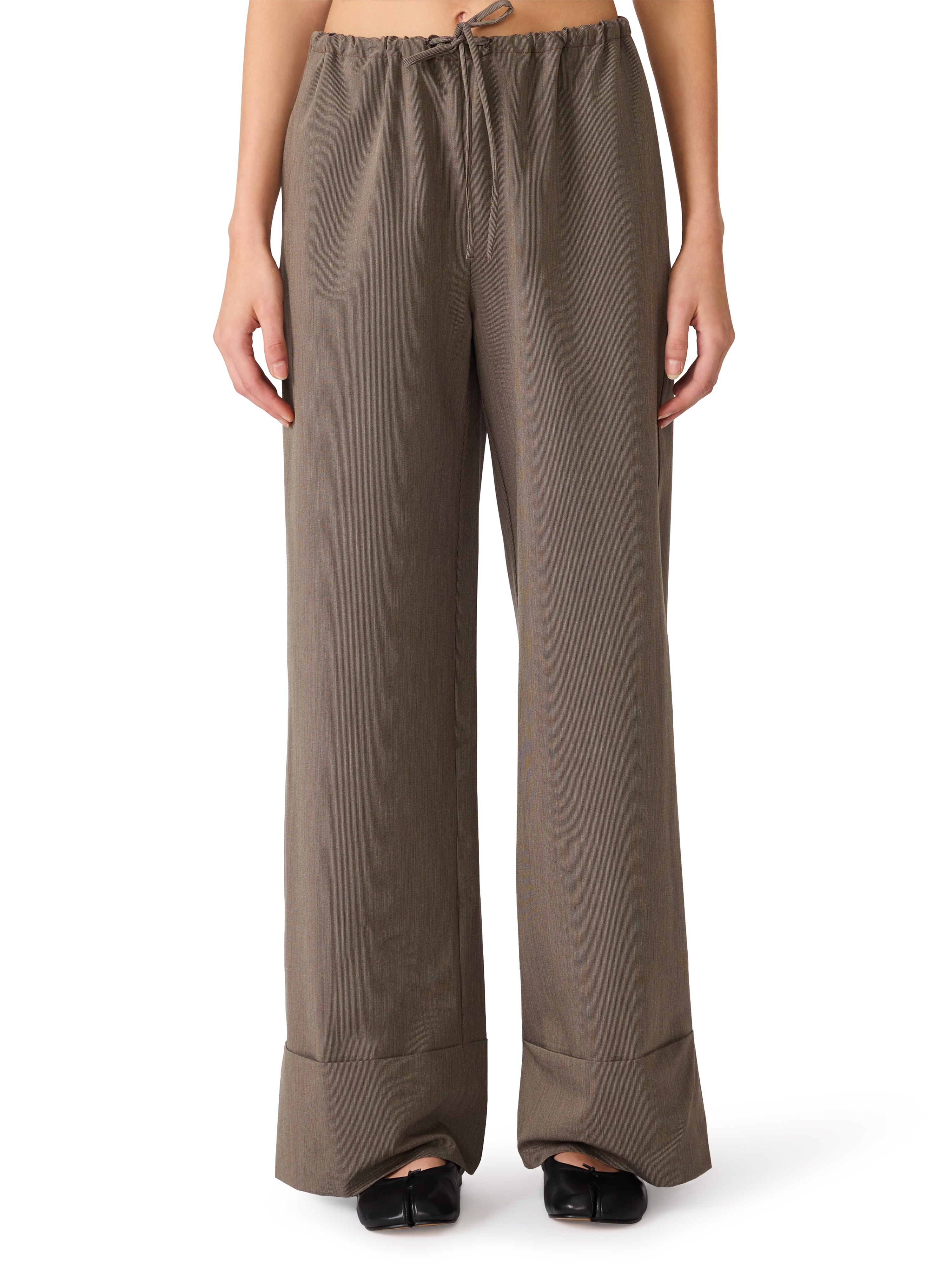 Model wearing relaxed wide-leg trousers with an elastic drawstring waistband and cuffed hem paired with black flats.