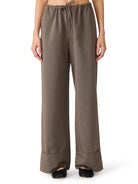 Model wearing relaxed wide-leg trousers with an elastic drawstring waistband and cuffed hem paired with black flats.