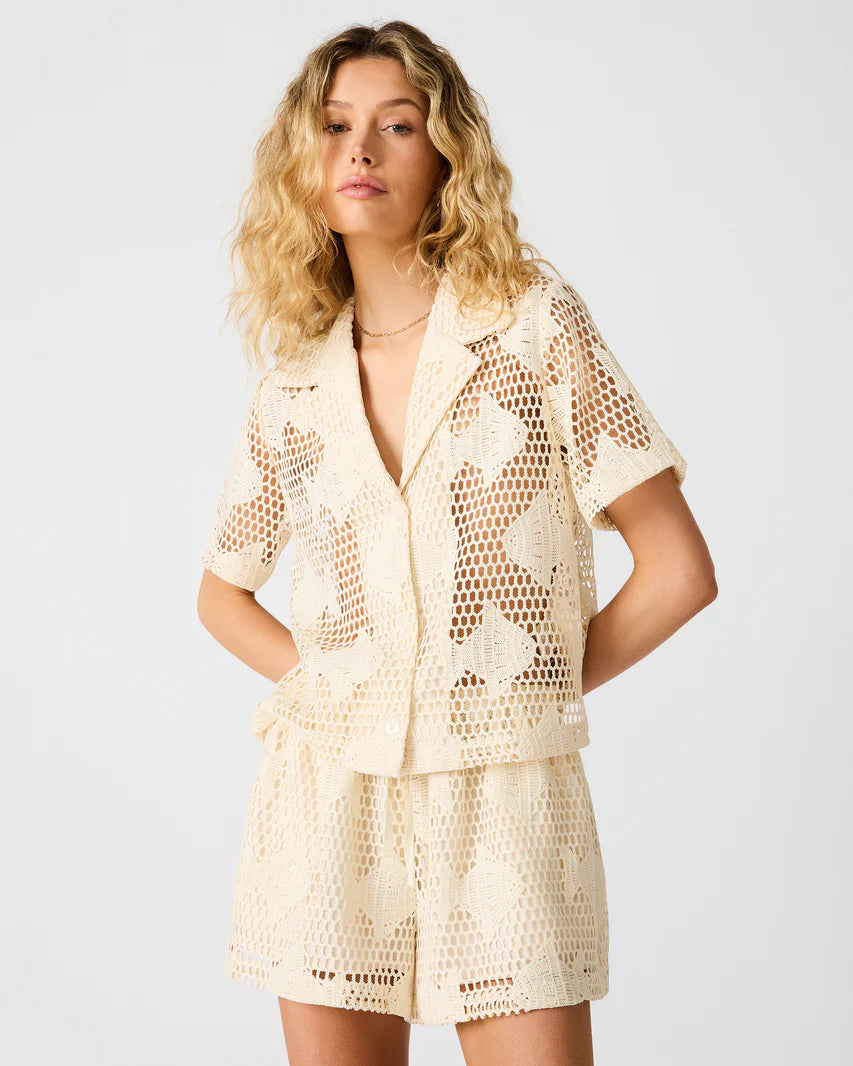 Model wearing a short sleeve crochet button-up top with matching shorts.