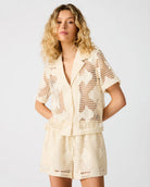 Model wearing a short sleeve crochet button-up top with matching shorts.