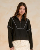 Woman wearing a quarter-zip sweater with contrast stitching detail.