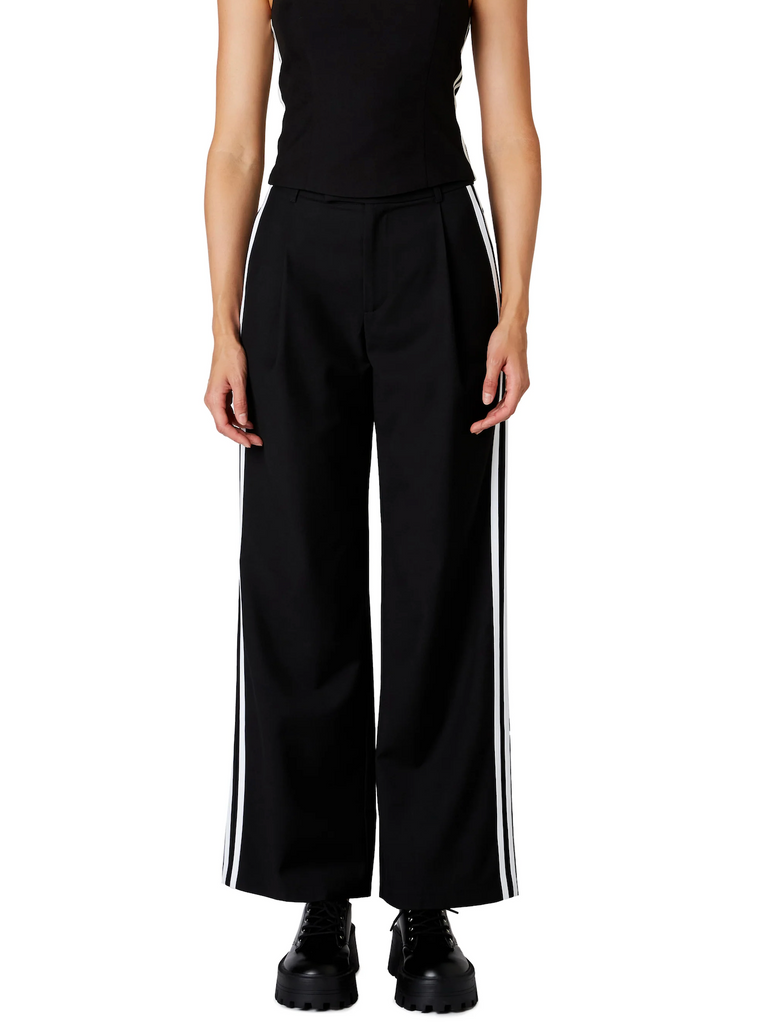 Nia Messi Trouser Black. This mid-rise pleated trouser features two contrast stripes at the side seam, wear them on their own or with the Kato Top for a cute sporty set.