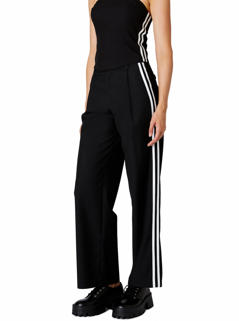 Nia Messi Trouser Black. This mid-rise pleated trouser features two contrast stripes at the side seam, wear them on their own or with the Kato Top for a cute sporty set.