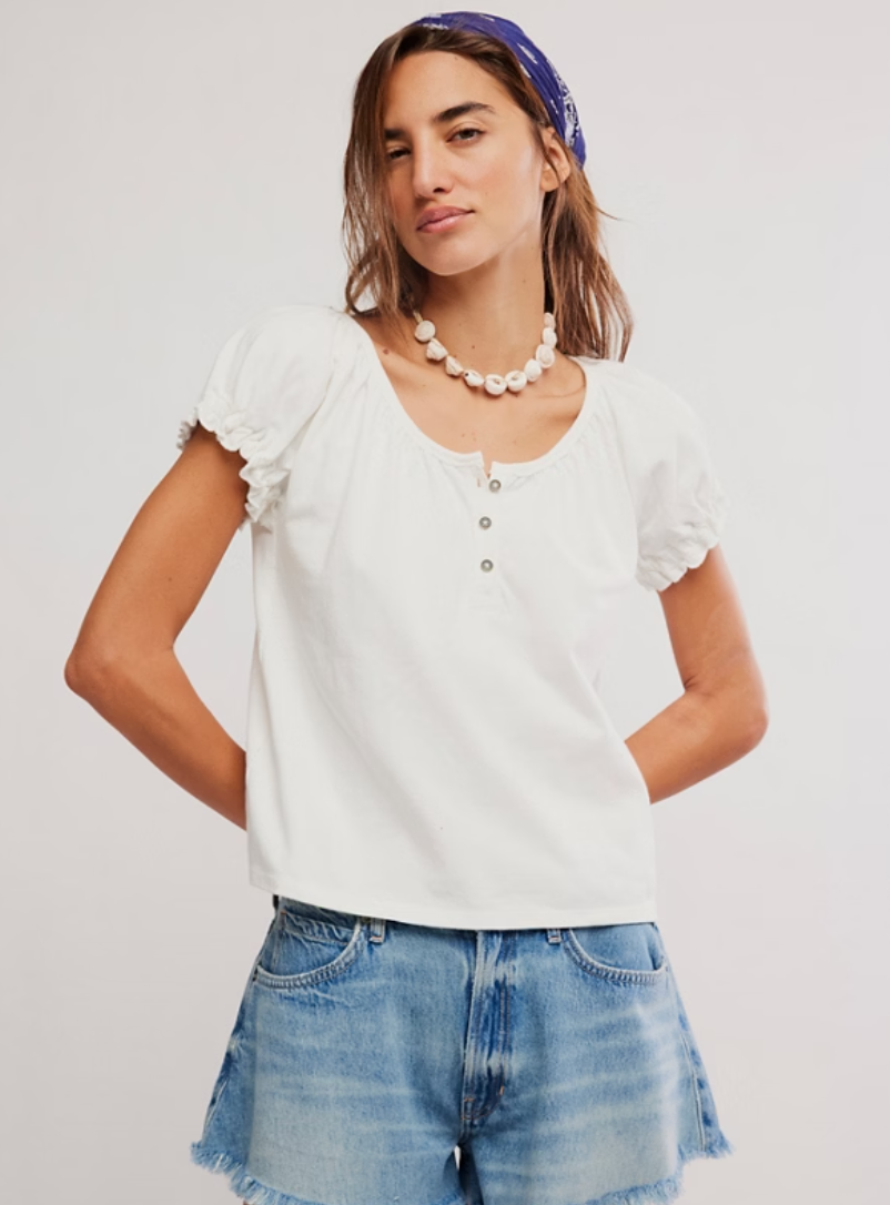 Woman wearing a ruffle sleeve henley top with a relaxed fit and button neckline, styled with casual bottoms
