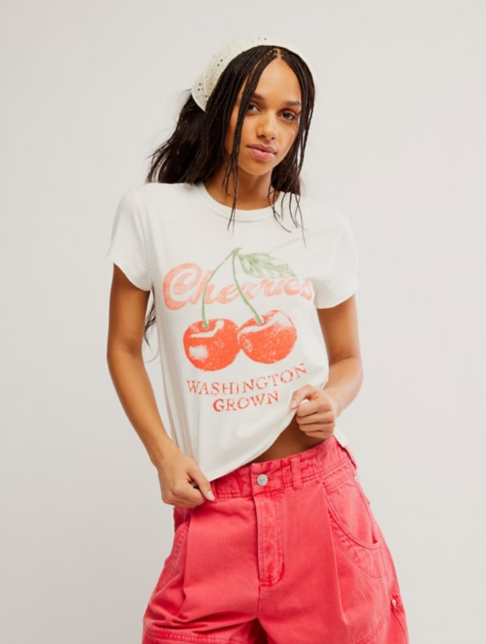 White graphic t-shirt with vintage cherry print and retro lettering paired with bright pink pants.