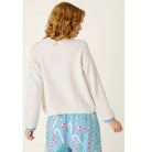 Ivory crewneck sweater with blue snowflake graphic, dropped shoulders, and contrasting blue cuffs
