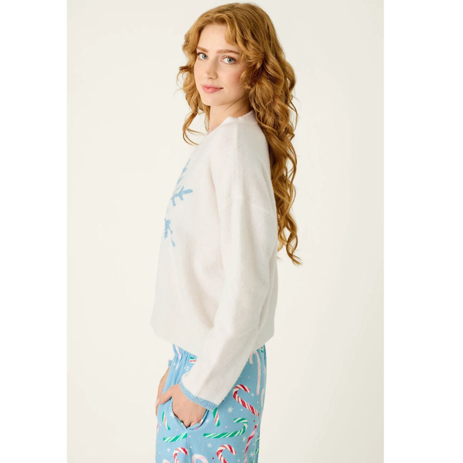 Ivory crewneck sweater with blue snowflake graphic, dropped shoulders, and contrasting blue cuffs