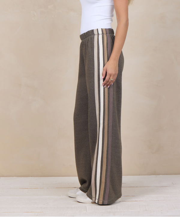 Woman wearing wide-leg heather fleece pants with a varsity side stripe.