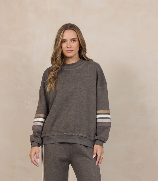 Woman wearing a heather fleece mockneck pullover with dropped shoulders and striped cuffs.