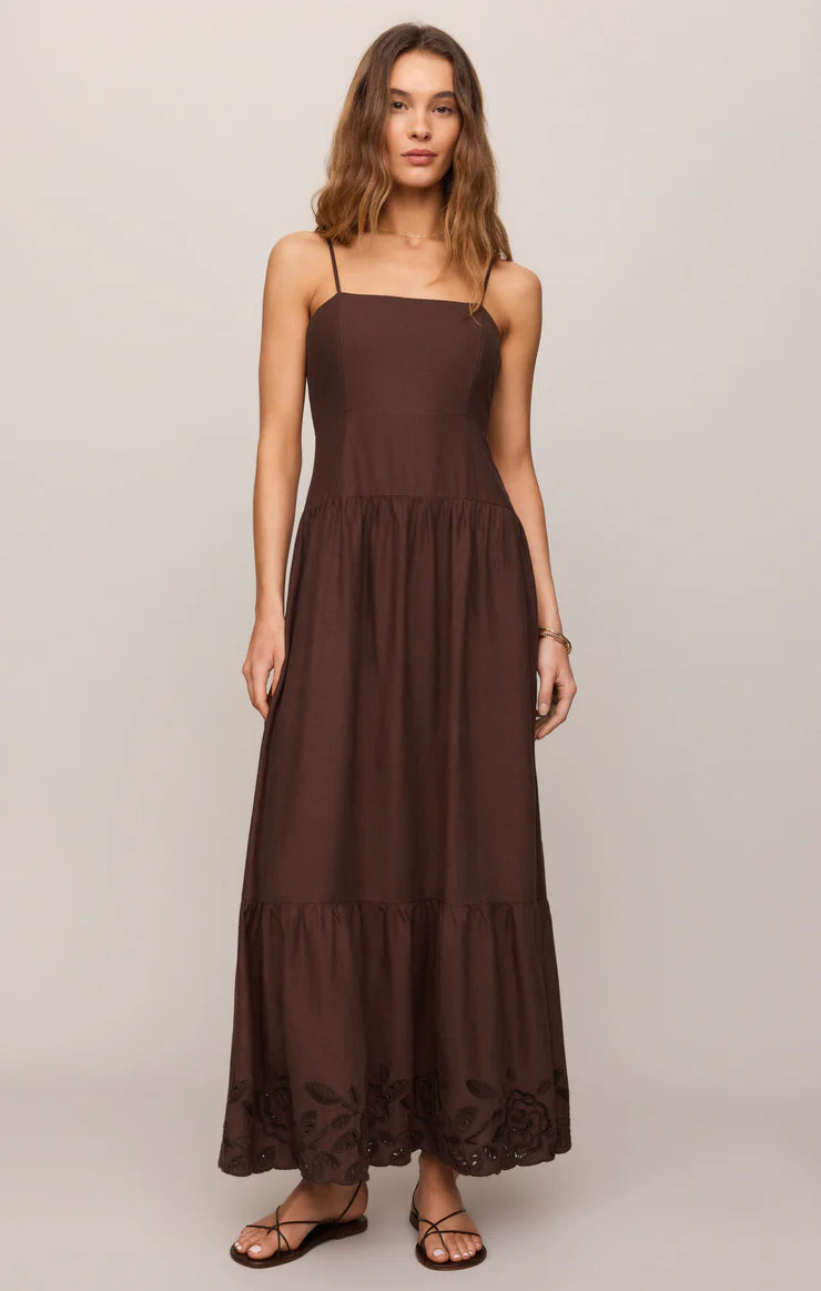 Model wearing a sleeveless maxi dress with a square neckline, adjustable spaghetti straps, and embroidered hem detailing.