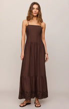 Model wearing a sleeveless maxi dress with a square neckline, adjustable spaghetti straps, and embroidered hem detailing.