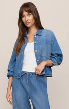 Relaxed button-front denim jacket with a collared neckline, oversized chest pocket, and an easy, lightweight fit layered over a tank top.