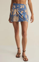 Woman wearing a printed wrap mini skirt with a side tie detail and lightweight fabric, styled with flat sandals