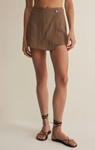 Lightweight wrap-style skort with an asymmetrical front overlay and metal button detail.