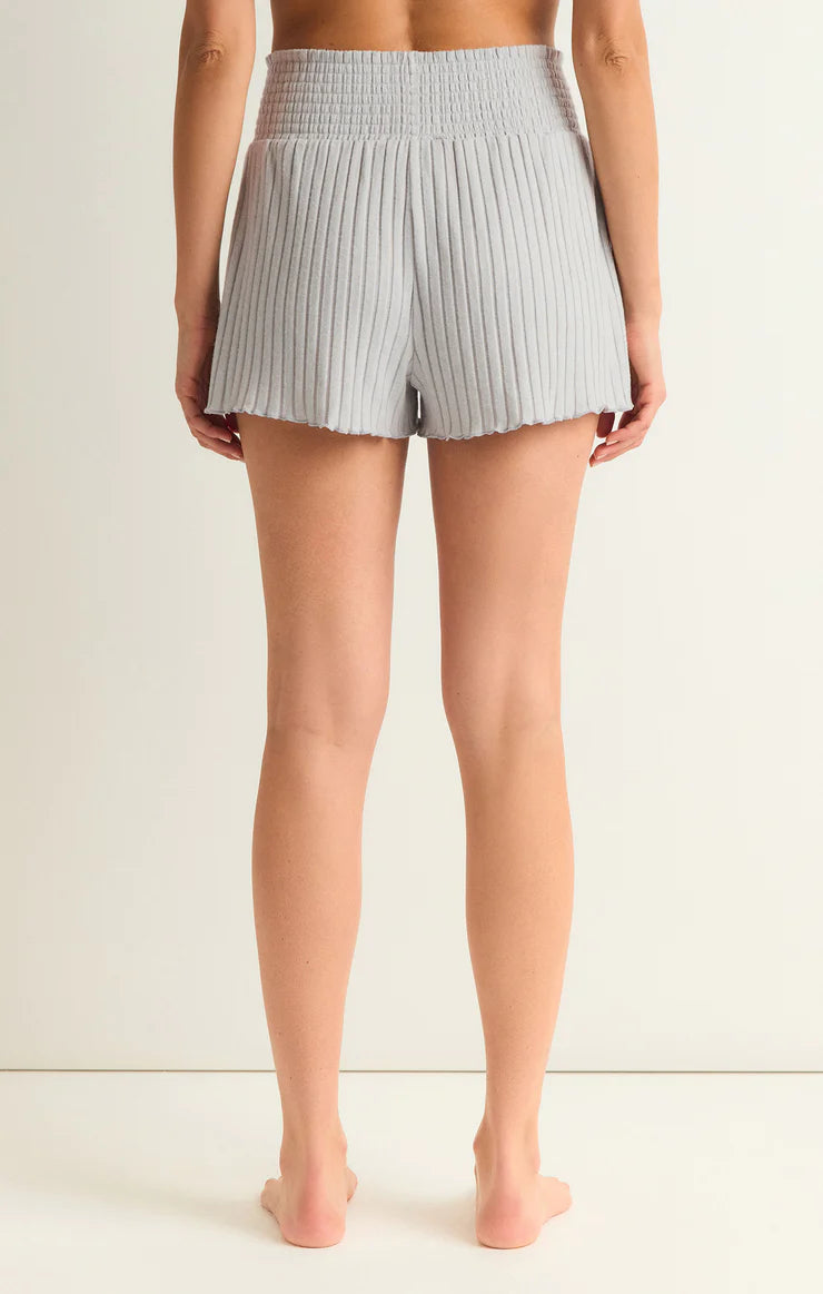 Z Supply Dawn Smocked Rib Short Platinum Grey. The Dawn Smocked Rib Short is a must have, made using a cozy silky rib fabric. The smocking detail is soft and flattering and the lettuce edge gives us all the feels with just the right amount of frills.