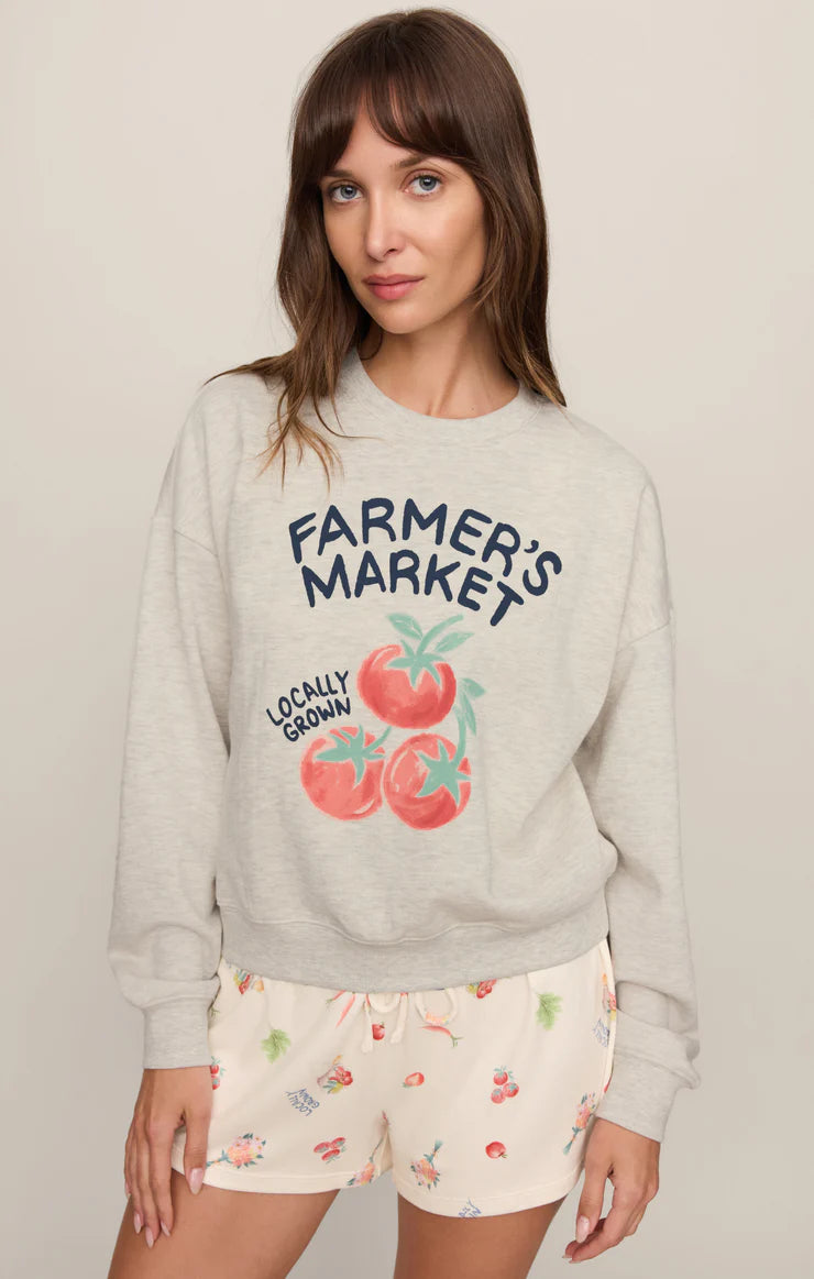Model wearing a relaxed-fit graphic sweatshirt featuring a vintage-inspired farmer's market tomato graphic paired with printed lounge shorts.