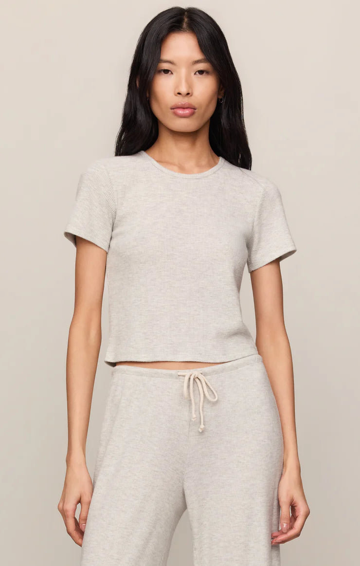 Model wearing a fitted crewneck knit T-shirt with short sleeves paired with matching wide-leg lounge pants.