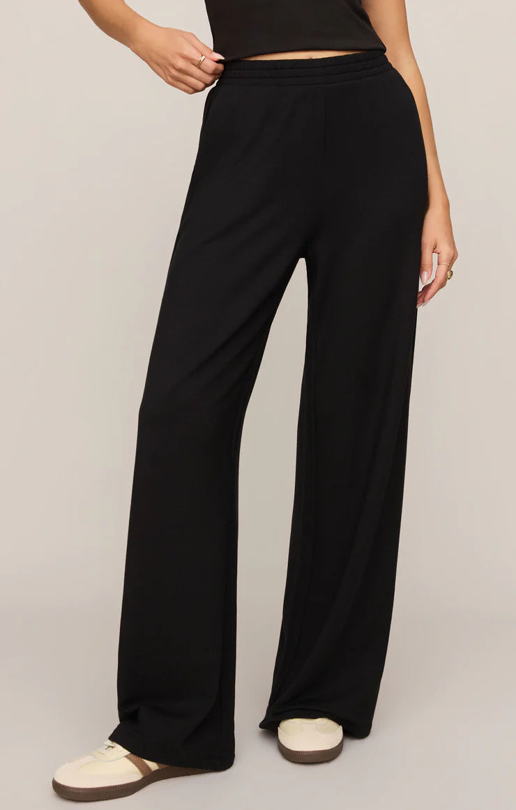 Model wearing ultra-soft black wide-leg lounge pants with a pull-on waistband and relaxed fit paired with sneakers.