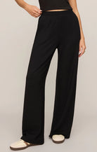Model wearing ultra-soft black wide-leg lounge pants with a pull-on waistband and relaxed fit paired with sneakers.