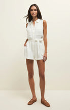 Sleeveless button-front romper with collar, patch pockets, and tie waist worn with woven flats