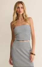 Woman wearing a striped strapless knit tube top with a fitted silhouette, styled with a matching skirt