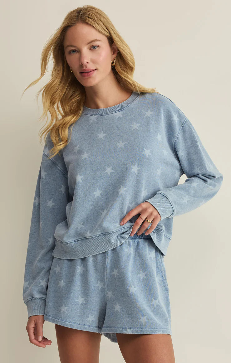 Soft crewneck sweatshirt with allover star print, relaxed fit, and long sleeves, styled with matching lounge shorts and sneakers
