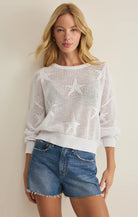 Open-knit sweater with star pattern, long sleeves, and relaxed fit styled with denim shorts
