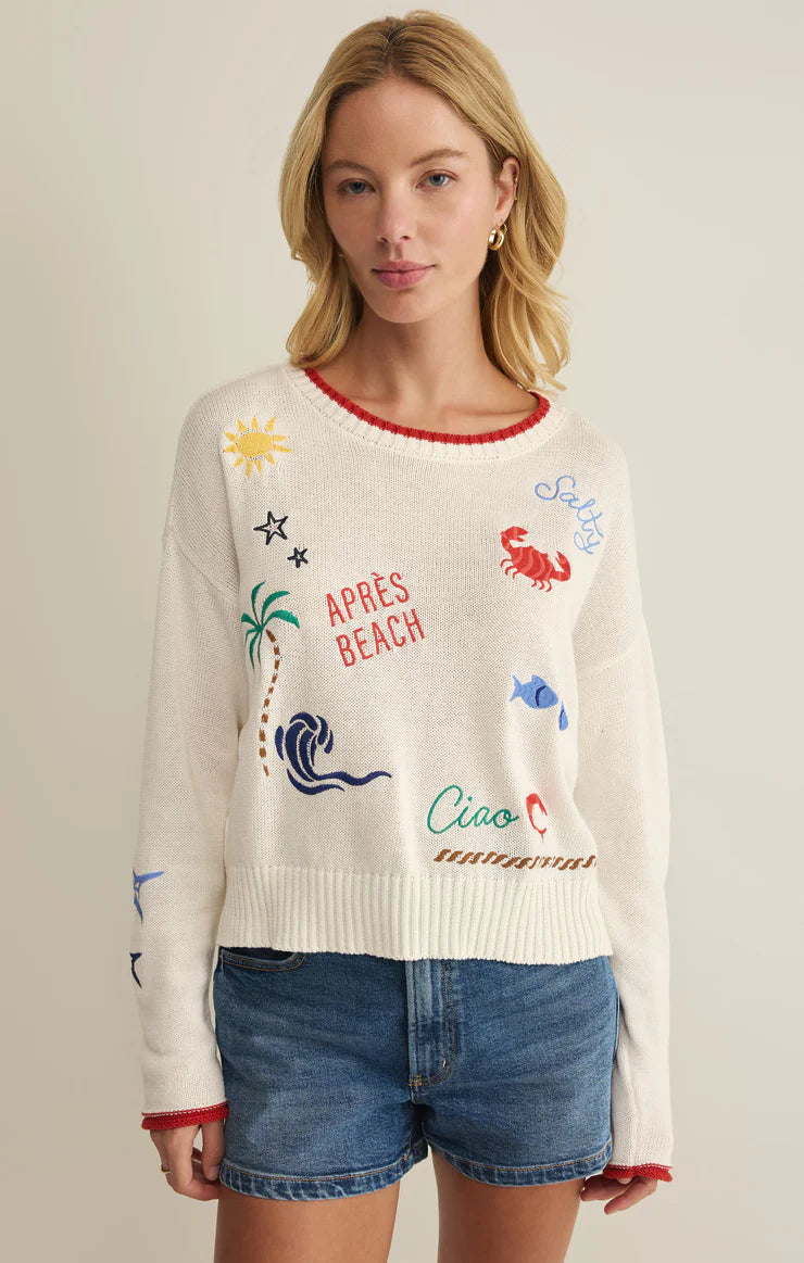 Lightweight knit sweater with playful beach-inspired embroidery, relaxed fit, and long sleeves, styled with denim shorts
