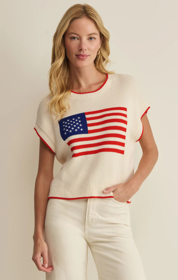 Model wearing a short sleeve knit sweater with a flag design and contrast trim.