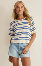 Woman wearing a striped short sleeve knit sweater with a relaxed fit, styled with denim shorts