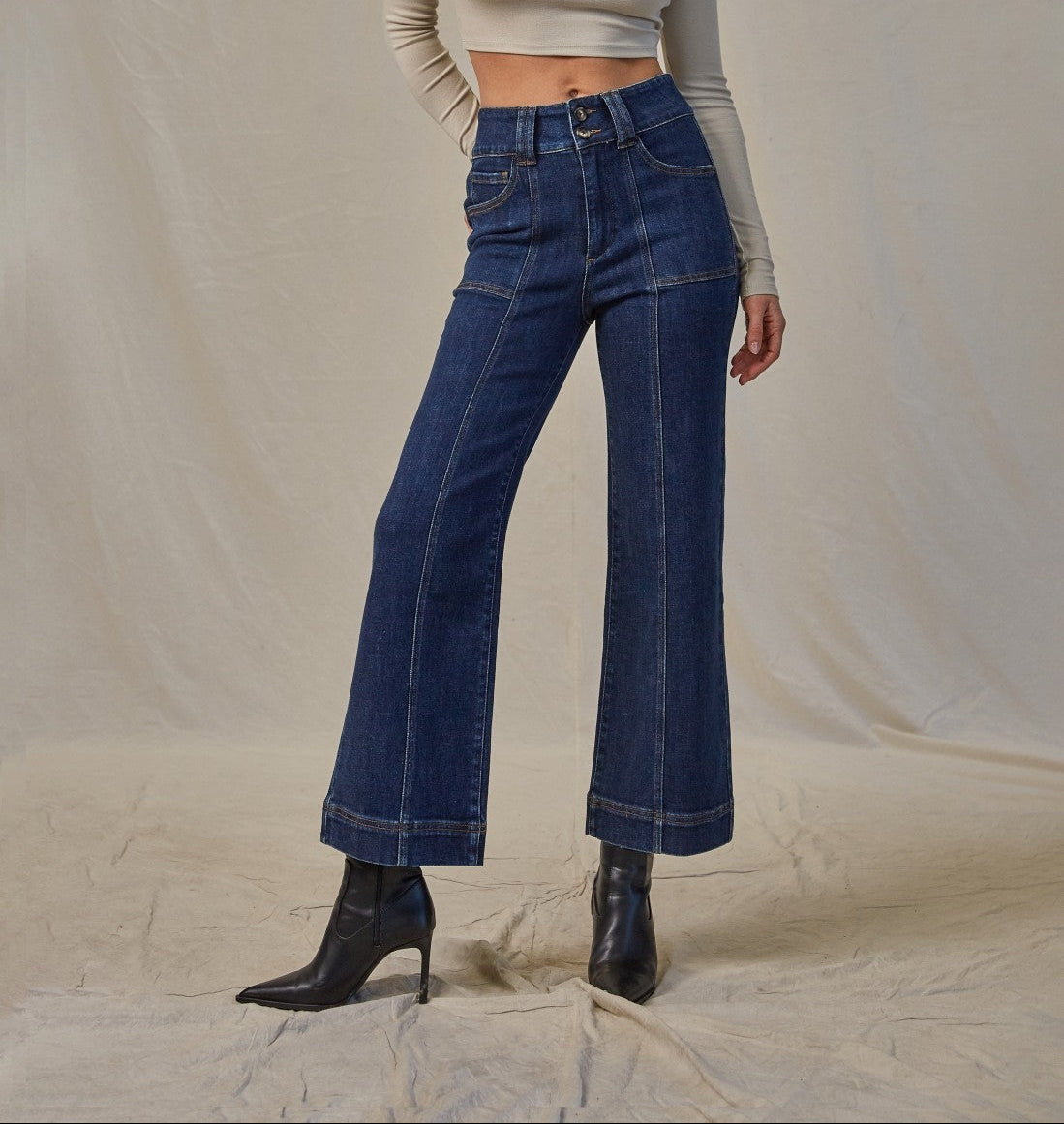 Woman wearing high-rise cropped flare jeans with a double-button waistband, patch pockets, and front seams.
