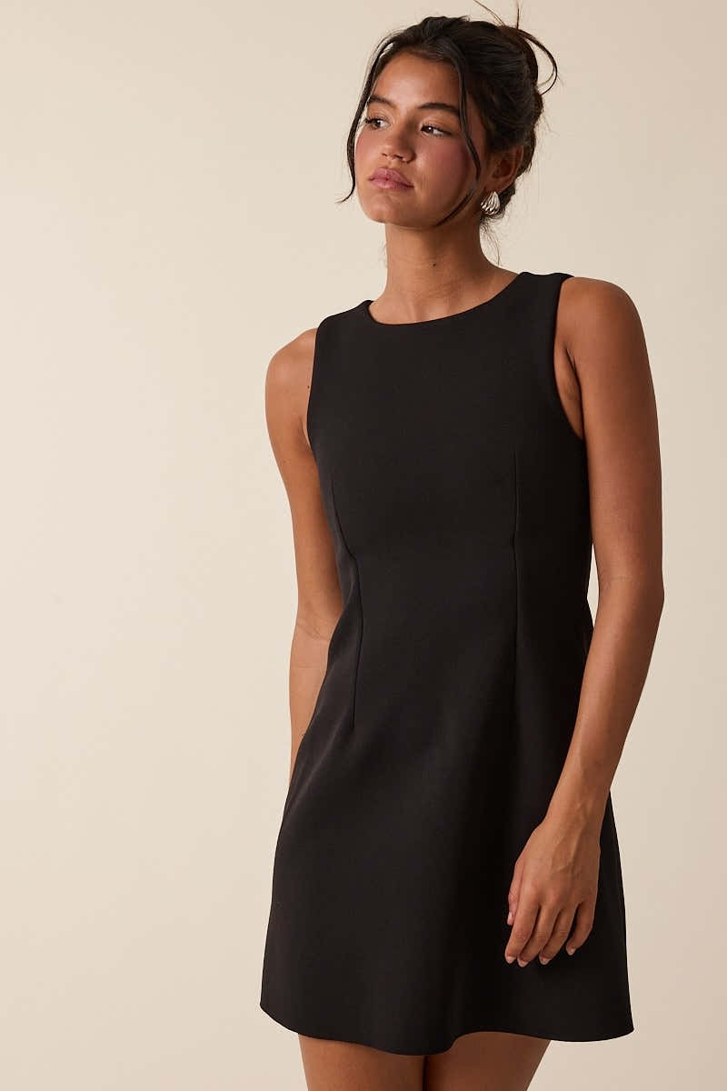 Model wearing a sleeveless mini dress with a fitted bodice and softly flared skirt.