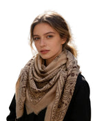 Woman wearing an oversized square scarf with a bandana-inspired paisley print and lightly fringed edges.