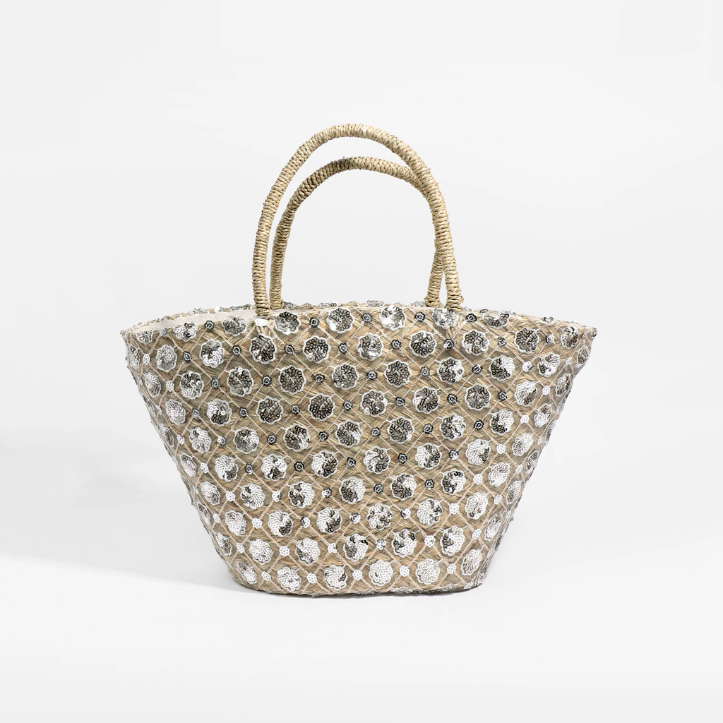 Make a chic statement with the Avi Bag in Sand, featuring silver-tone embellished flowers for a touch of glamour. This stylish straw basket offers ample storage, a secure zipped closure, and interior pockets, making it perfect for everyday use or travel.